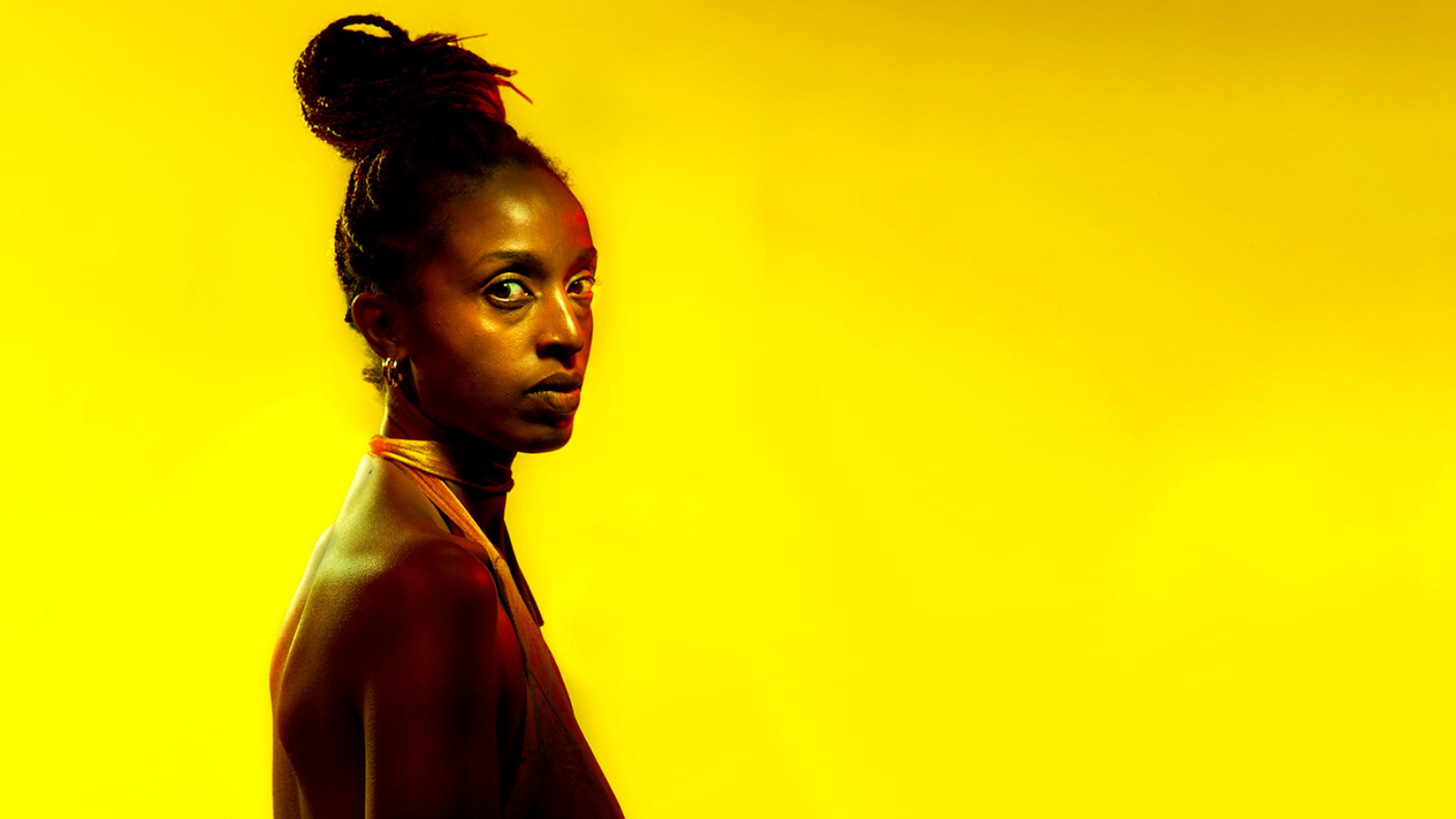 A black woman in silhouette before a bright yellow background.