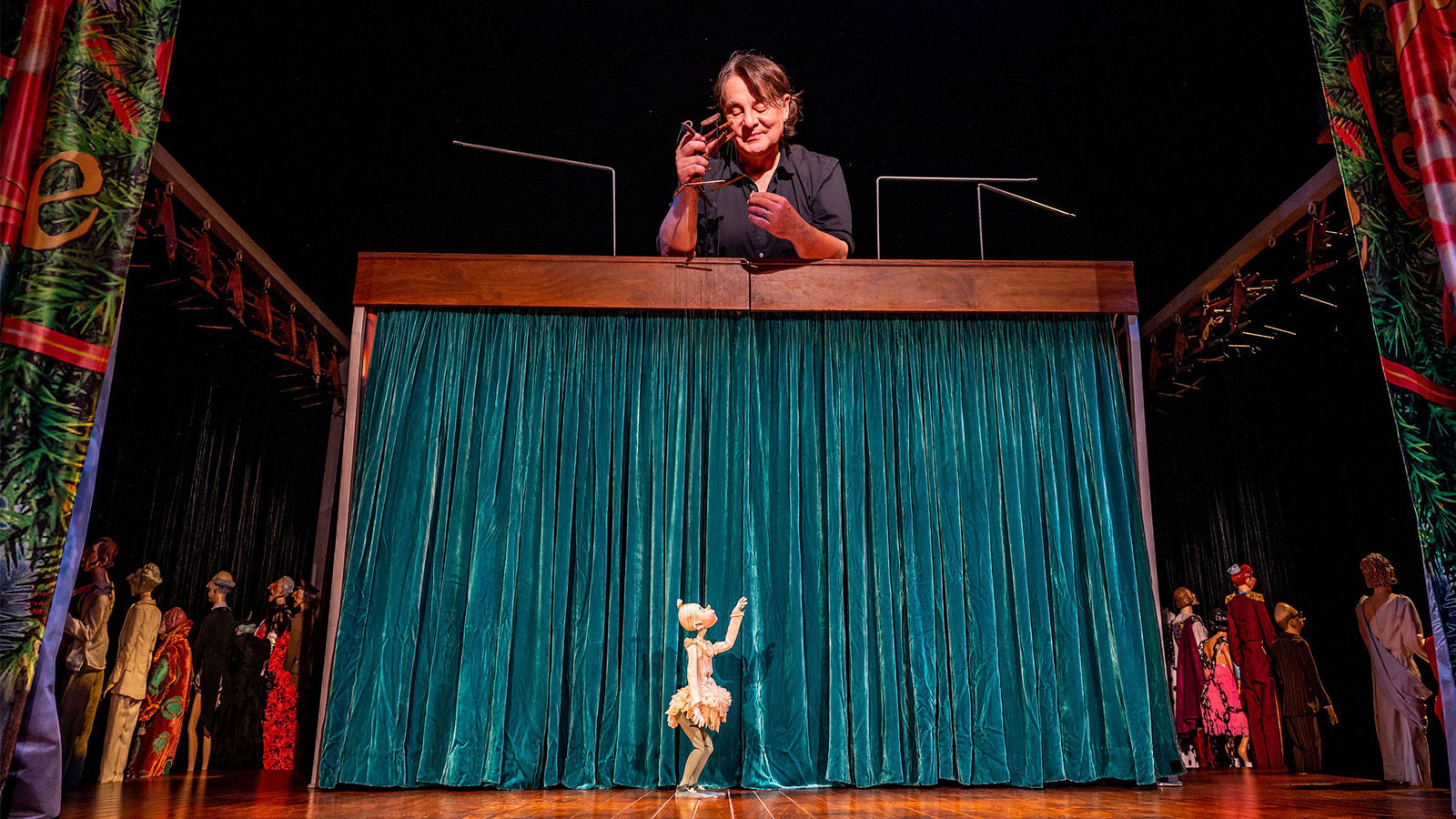 Ronnie Burkett looking down at marionette on stage. 